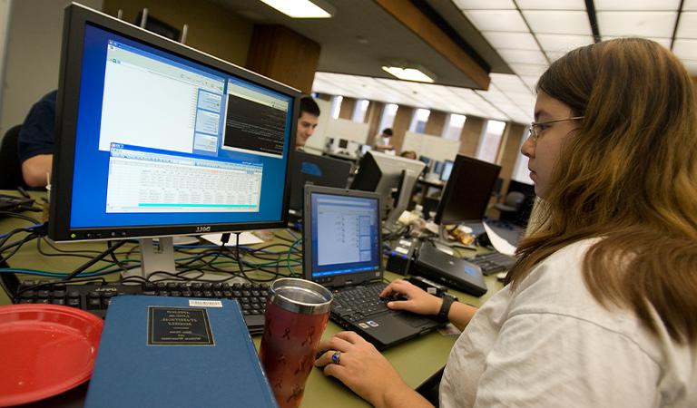 Student looks at charts on a computer screen in a computer lab.